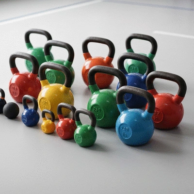 Różne rozmiary kettlebell ułożone na podłodze siłowni